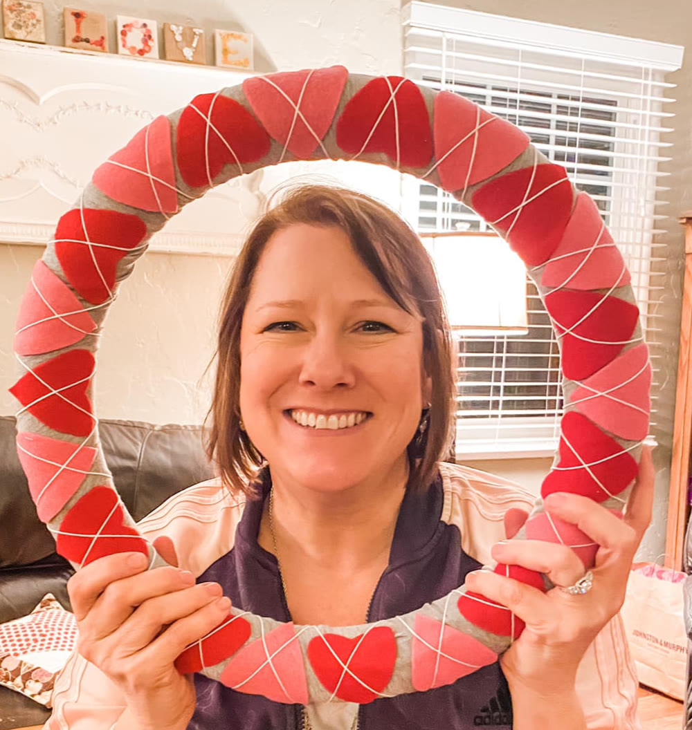 Ellen holding a felt heart wreath she made at Auburn Sewing Studio
