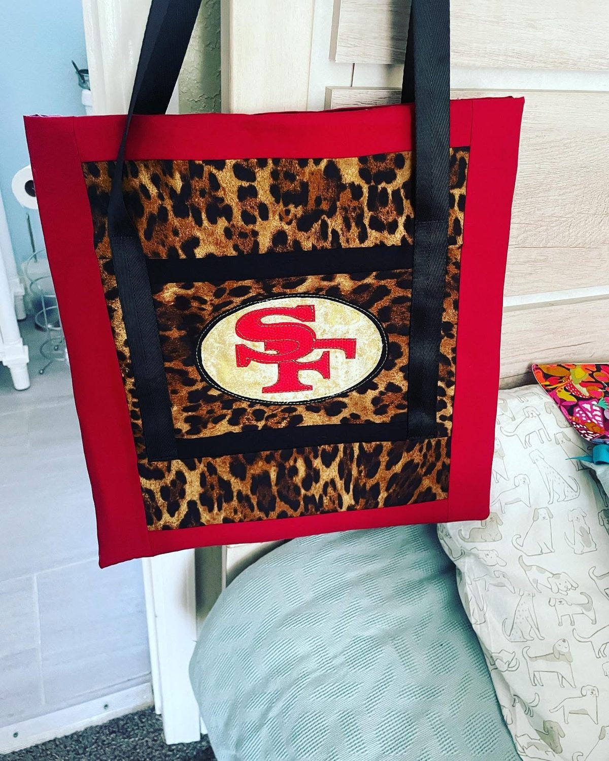 A red tote bag with a leopard print panel and an appliqued SF oval