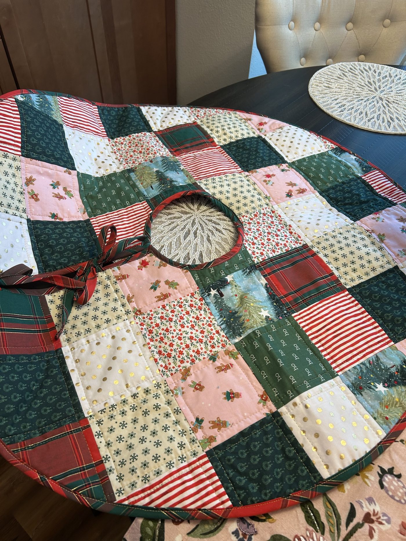 A round patchwork Christmas tree skirt in plaid, gingerbread and gold-dot fabrics, made at the studio